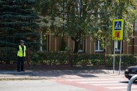 Policjant sprawdza oznakowanie przejścia dla pieszych przy szkole.