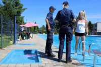 policjanci rozmawiają z wypoczywającymi nad basenem
