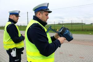 Policjanci z ruchu drogowego sprawdzają urządzenie służące do pomiaru prędkości przejeżdżających pojazdów.