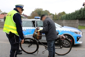 Zdjęcie przedstawia policjanta, rowerzystę oraz radiowóz.