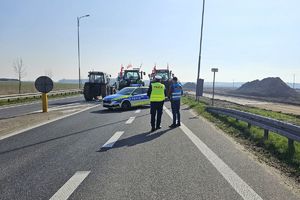 Zdjęcie przedstawia umundurowanego oraz nieumundurowanego policjanta, radiowóz oraz ciągniki rolnicze.